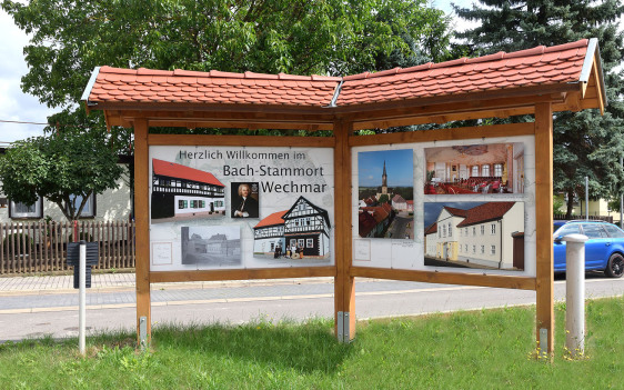Im Foto zum Bachort Wechmar ist in der Mitte ein einstöckiges Gebäude mit roten Ziegeln. Davor ist ist ein Pakrplatz, rechts eine Hecke, oben noch Blätter vom Baum: es ist die Verwaltung von Wechmar.
