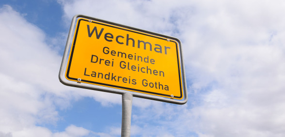 Im Bild sieht man nur und ausschließlich, von unten nach oben fotografiert, das Ortseingangsschild vom Bachort Wechmar. Der Himmel dahinter ist wolkenlos und blau.